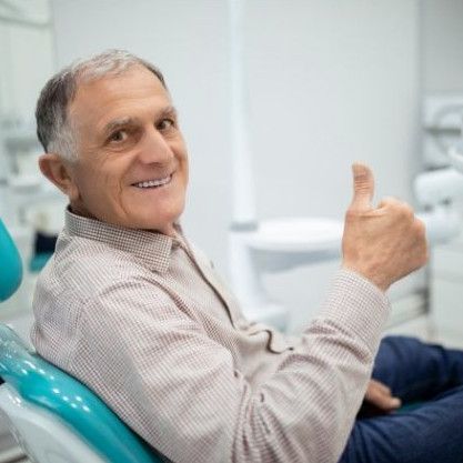 Older gentleman gives a thumbs up to dental care