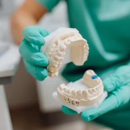 Hands of a dental laboratory tech showing a dental impression